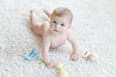 Renkli pastel antika çıngıraklı oyuncakla oynayan şirin bir bebek. Yeni doğmuş bir çocuk, küçük bir kız kameraya bakıyor ve emekliyor. Aile, yeni hayat, çocukluk, başlangıç konsepti. Bebek yakalama.