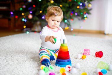 Evde ya da çocuk odasında eğitici oyuncaklarla oynayan sevimli, güzel bir kız bebek. Mutlu sağlıklı çocuk renkli ahşap çocuk oyuncak piramidiyle eğleniyor. Çocuk farklı yetenekler öğreniyor.