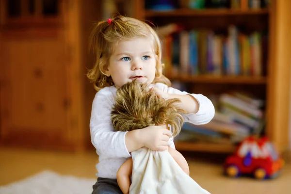 Adorável bonito pequena menina brincando com boneca. Criança bebê saudável feliz se divertindo com jogo de papel, jogando mãe em casa ou berçário. Filha ativa com brinquedo — Fotografia de Stock