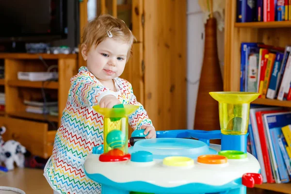 Feliz niña alegre jugando con diferentes juguetes de colores en casa. Adorable niño sano que se divierte jugando solo. Ocio activo en interiores, guardería o escuela de juegos. —  Fotos de Stock