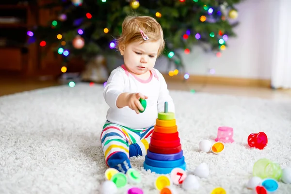 사랑스럽고 귀여운 작은 여아가 집이나 보육원에서 교육용 장난감을 가지고 놀고 있다. 건강하고 건강 한 아이가 화려 한 나무 소년 장난감 피라미드를 가지고 놀고 있습니다. 다른 기술을 배우는 아이. — 스톡 사진