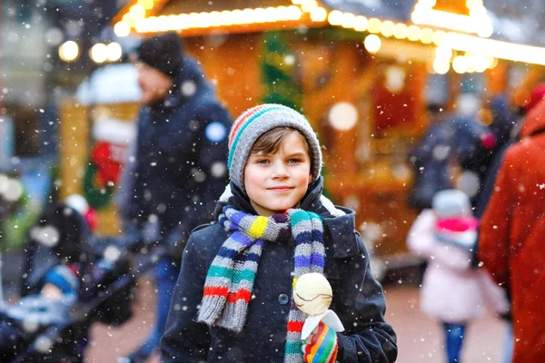 在传统的德国圣诞市场上，一个可爱的小男孩正在吃着覆盖着水果苹果的白色巧克力。雪天期间，德国传统家庭市场上的快乐孩子. — 图库照片
