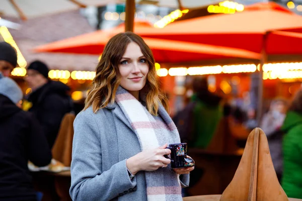 Belle jeune femme buvant du punch chaud, vin chaud sur le marché de Noël allemand. Fille heureuse en vêtements d'hiver avec des lumières sur le fond le jour de neige d'hiver à Berlin, Allemagne. — Photo