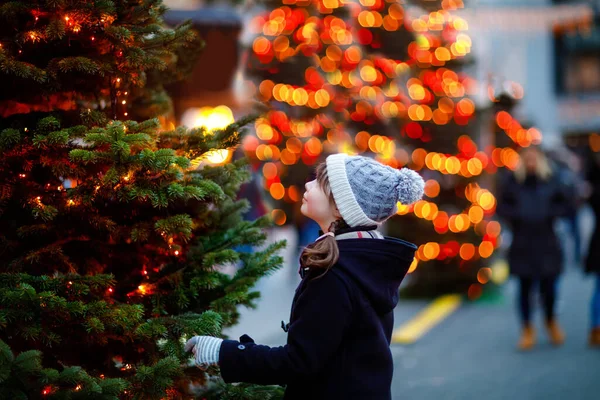 Küçük tatlı kız şiddetli kar yağışında geleneksel Noel pazarında eğleniyor. Mutlu çocuk Almanya 'da geleneksel aile pazarının tadını çıkarıyor. Aydınlatılmış xmas ağacının yanında duran liseli kız. — Stok fotoğraf