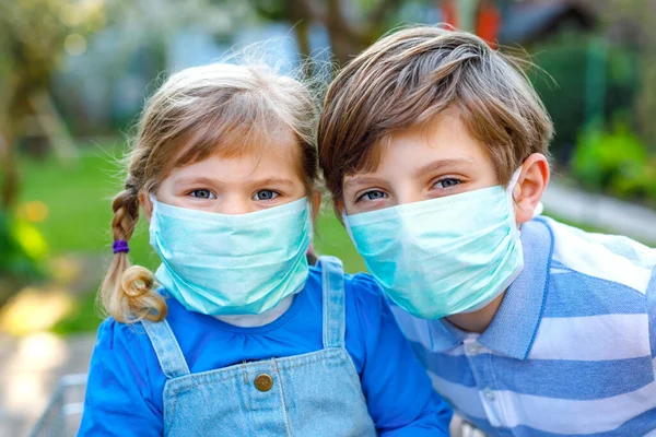 Dos niños, la niña y el niño de la escuela en máscara médica como protección contra la enfermedad pandémica por coronavirus. Niños hermanos con carrito de la compra utilizando equipo de protección como lucha con covid 19. — Foto de Stock