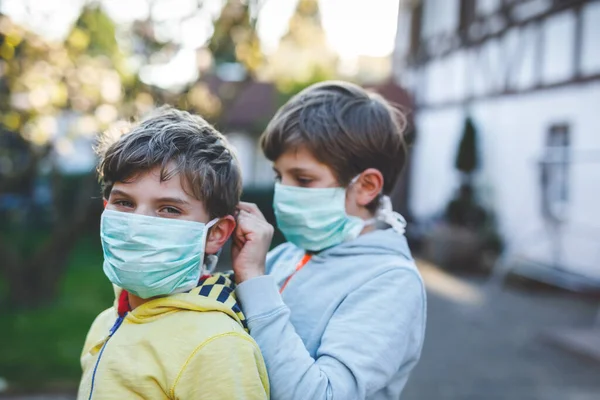 Dois miúdos com máscara médica como protecção contra a doença do coronavírus pandémico. Crianças, irmãos encantadores e melhores amigos usando equipamentos de proteção como luta contra o covid 19. — Fotografia de Stock