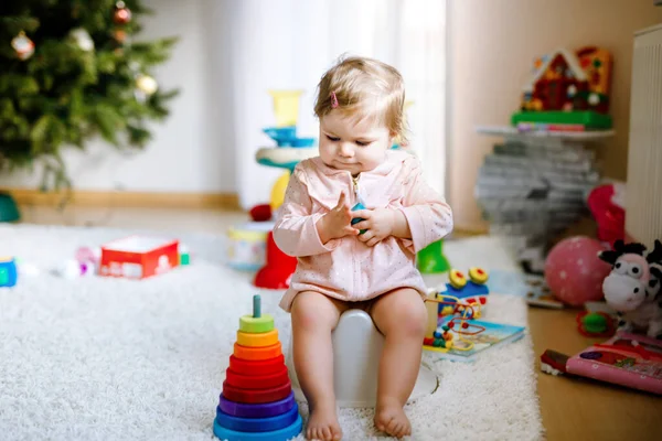 Close-up van schattige kleine 12 maanden oud peuter baby meisje kind zittend op potje. Een kind dat met educatief houten speelgoed speelt. Toilettrainingsconcept. Baby leren, ontwikkelingsstappen — Stockfoto