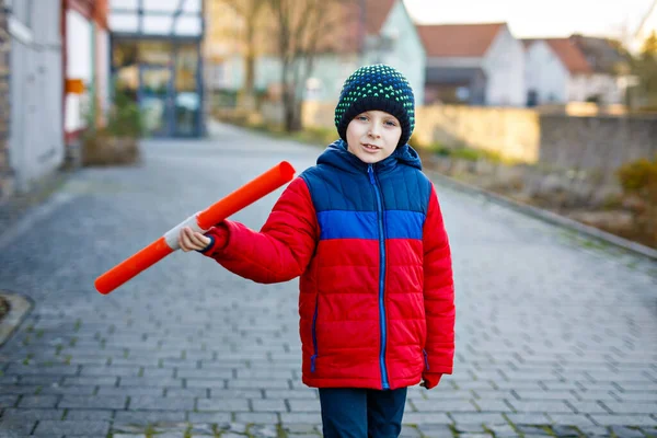 İlkokul çocuğu soğuk kış gününde okula yürüyordu. Mutlu çocuk şehir caddesinde eğleniyor. Renkli kış giysileri içinde sırt çantalı bir öğrenci proje için bir şeyler tutuyor. — Stok fotoğraf