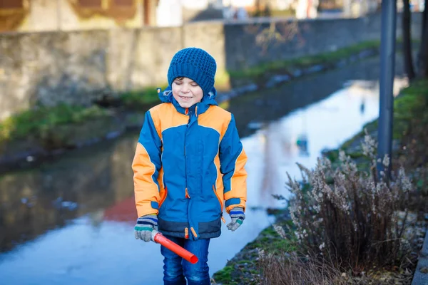 Niño de la escuela primaria caminando a la escuela en el frío día de invierno. Niño feliz en ropa de invierno caliente empujando la puerta a la escuela, al aire libre. —  Fotos de Stock