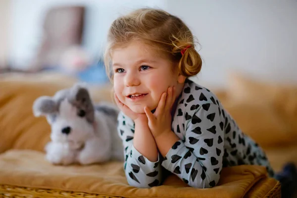 Linda niña pequeña en pijama de ropa de dormir viendo dibujos animados o película en la televisión. Feliz bebé sano en casa. — Foto de Stock