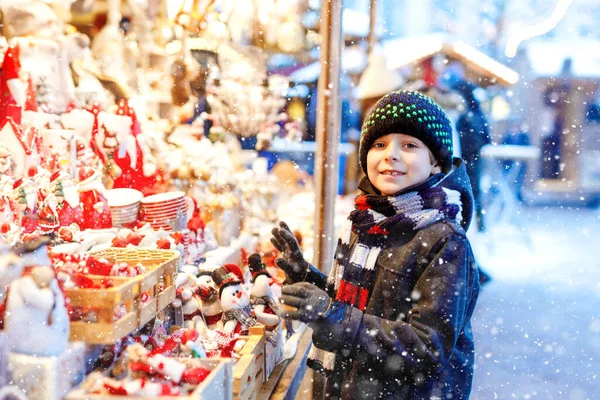 Pequeño niño lindo seleccionando decoración en el mercado de Navidad. Hermoso niño comprando juguetes y adornos decorativos cosas para el árbol. Mercado de Navidad en Alemania. — Foto de Stock