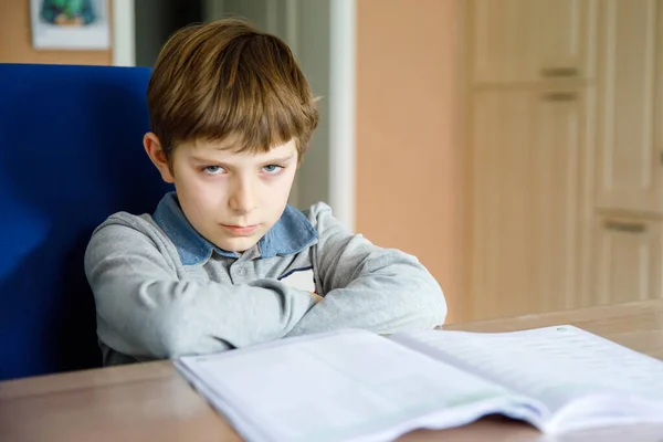 Upset school kid boy making homework during quarantine time from corona pandemic disease. Crying and sad boy frustrating staying at home.