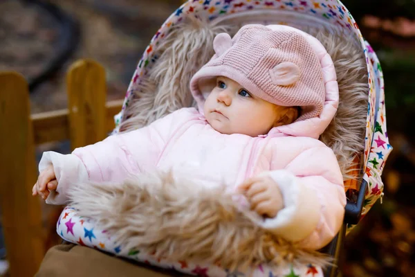 Cute little beautiful baby girl sitting in the pram or stroller on winter evening on christmas market — Stock Photo, Image