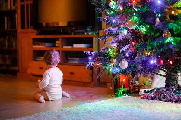 Roztomilé holčička drží barevné světla girland v roztomilých rukou. Malé dítě ve slavnostním oblečení zdobí vánoční stromeček s rodinou. První oslava tradičního svátku Weihnachten — Stock fotografie