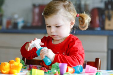 Renkli killi, sevimli, küçük bir kız. Sağlıklı bebek oyun oynuyor ve oyun hamurundan oyuncaklar yapıyor. Küçük çocuk kil kalıp ve öğrenim
