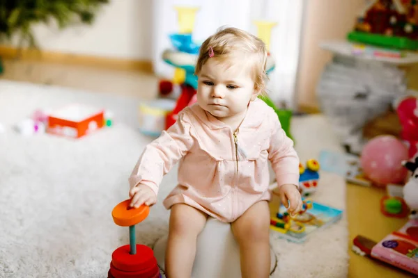 Close-up van schattige kleine 12 maanden oud peuter baby meisje kind zittend op potje. Een kind dat met educatief houten speelgoed speelt. Toilettrainingsconcept. Baby leren, ontwikkelingsstappen — Stockfoto