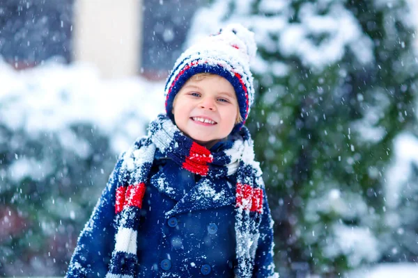 Bonito criança engraçada em roupas coloridas de moda de inverno se divertindo e brincando com a neve, ao ar livre durante a queda de neve. Atividades ao ar livre lazer com crianças. Garoto e criança pegando flocos de neve. — Fotografia de Stock