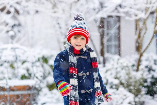 Lindo niño divertido en ropa de moda de invierno colorido divertirse y jugar con la nieve, al aire libre durante las nevadas. Activo ocio al aire libre con niños. Niño y niño cogiendo copos de nieve. —  Fotos de Stock