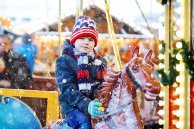 Atlı karıncaya binen sevimli küçük çocuk Noel panayırında ya da markette, açık havada atlıkarıncayı dolaşır. Mutlu çocuk Almanya 'da geleneksel aile Xmas pazarında eğleniyor.