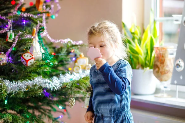 Entzückende Kleinkind Mädchen hält kleinen Spiegel und steht am Weihnachtsbaum d. Kleines Kind in festlicher Kleidung Feier Weihnachten — Stockfoto