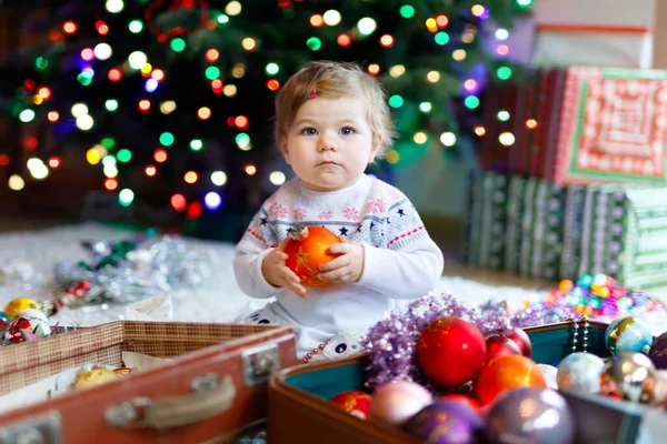 Söt liten flicka som håller färgglada ljus körtel i söta händer. Små barn i festliga kläder dekorera julgran med familj. Första firandet av traditionell semester som heter Weihnachten — Stockfoto