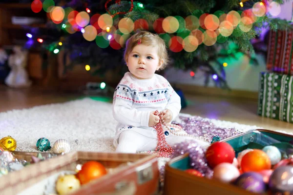 Entzückendes kleines Mädchen mit bunten Lichtergirlanden in niedlichen Händen. Kleines Kind in festlicher Kleidung schmückt Weihnachtsbaum mit Familie. Erstes Fest des traditionellen Feiertags namens Weihnachten — Stockfoto