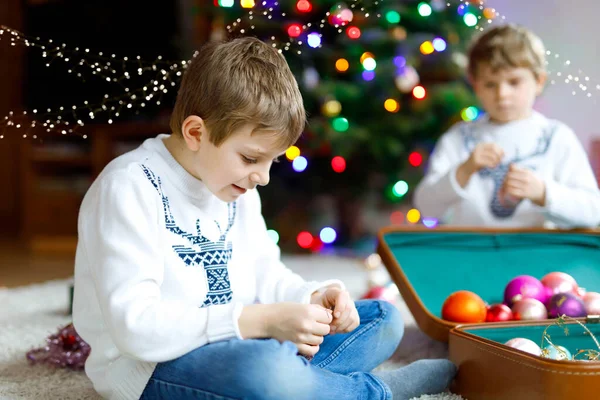 Beautiful kid boy with olorful vintage xmas toys and balls in old suitcase. children decorating Christmas tree — Stock Photo, Image