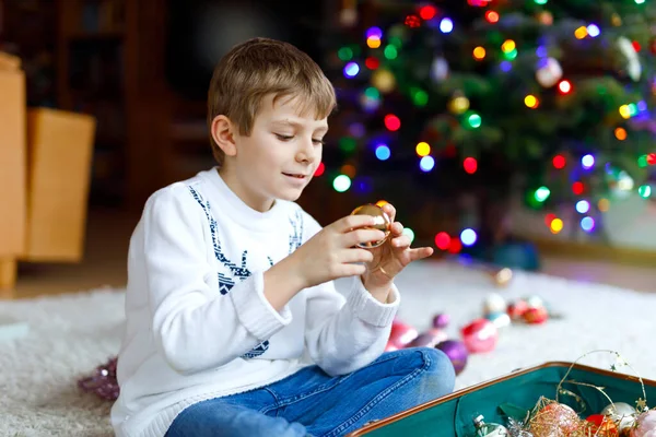 美しい子供の男の子とカラフルなヴィンテージのクリスマスのおもちゃやボール。クリスマスツリーを飾る子供 — ストック写真