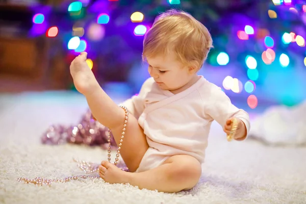 형형색색의 조명을 귀여운 손으로 들고 있는 사랑 스러운 어린 소녀. 크리스마스 트리를 가족들로 장식하는 축제 복을 입은 어린아이. 웨 덴 나크 텐이라고 불리는 전통 명절의 첫 번째 기념행사 — 스톡 사진