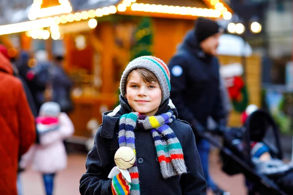 Little cute kid boy eating white chocolate covered fruit apple on skewer on traditional German Christmas market. Happy child on traditional family market in Germany during snowy day. — Stock Photo, Image