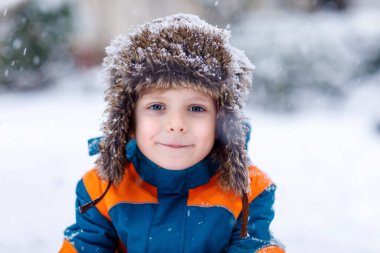 Mutlu çocuk kışın karla eğleniyor.