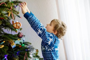 Küçük çocuk Noel ağacından Noel süslerini indiriyor. Kutlamalardan sonra aile ağacı kaldırır ve imha eder. Ren geyikleriyle şenlikli kıyafetler giyen çocuklar..