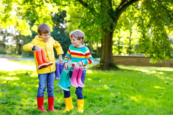 Duas crianças meninos, irmãos bonitos com muitas botas de chuva coloridas. Crianças em diferentes botas de borracha e jaquetas. Calçado para queda chuvosa. Gêmeos saudáveis e melhores amigos se divertindo ao ar livre — Fotografia de Stock