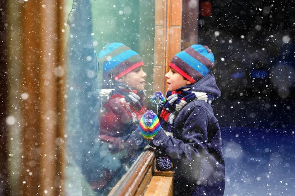 在圣诞市场上，可爱的小健康的学童男孩。喜形于色的孩子穿着时尚的冬季服装,在橱窗里购物,装饰着礼物,圣诞树.降雪，降雪 — 图库照片