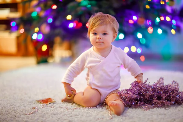 Adorable bébé fille tenant guirlande de lumières colorées dans des mains mignonnes. Petit enfant en vêtements de fête décorant l'arbre de Noël en famille. Première célébration de la fête traditionnelle appelée Weihnachten — Photo