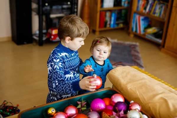 Linda niña y niño quitando las decoraciones navideñas del árbol de Navidad. niños, hermanos, hermanos y hermanas sosteniendo juguetes vintage. Familia después de la celebración quitar y deshacerse del árbol —  Fotos de Stock