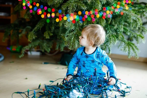 Menina bonito derrubando decorações de férias da árvore de Natal. criança segurando guirlanda luz. Família após celebração remover e descartar árvore — Fotografia de Stock