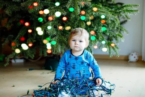 Nettes kleines Mädchen, das die Weihnachtsdekoration vom Weihnachtsbaum abnimmt. Kind mit Lichterkranz. Familie nach Feier Baum entfernen und entsorgen — Stockfoto