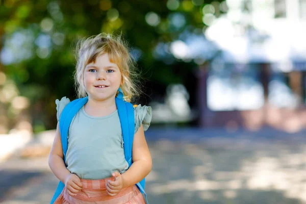 Nettes kleines entzückendes Kleinkind Mädchen an ihrem ersten Schultag. Gesunde schöne Baby zu Fuß in die Vorschule und den Kindergarten. Glückliches Kind mit Rucksack auf der Straße der Stadt, im Freien. — Stockfoto