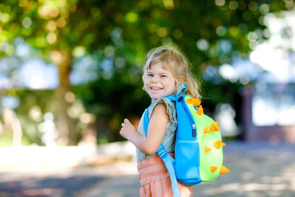 Nettes kleines entzückendes Kleinkind Mädchen an ihrem ersten Schultag. Gesunde schöne Baby zu Fuß in die Vorschule und den Kindergarten. Glückliches Kind mit Rucksack auf der Straße der Stadt, im Freien. — Stockfoto