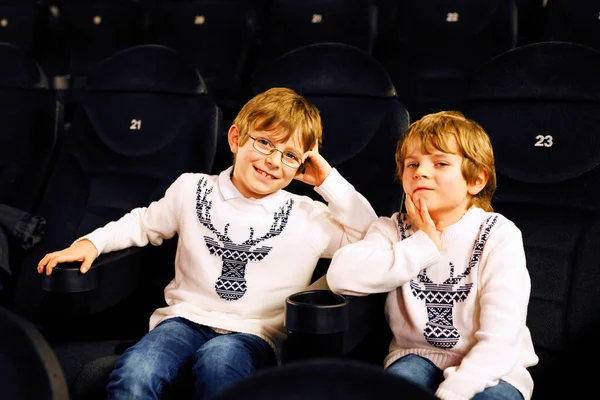 Dwóch uroczych blondyneczek czekających na film w kinie. Rodzeństwo, bliźniaki i bracia dobrze się bawią podczas oglądania filmów. Najlepsi przyjaciele na miejscach w ciemnym pokoju. — Zdjęcie stockowe