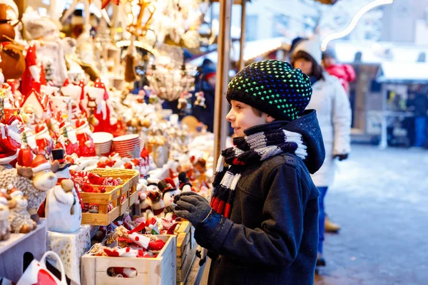 Little cute kid boy selecting decoration on Christmas market. Beautiful child shopping for toys and decorative ornaments stuff for tree. Xmas market in Germany. — Stock Photo, Image