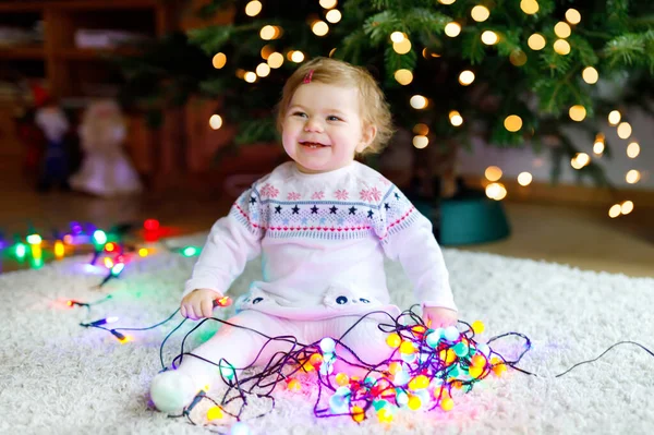 Söt liten flicka som håller färgglada ljus körtel i söta händer. Små barn i festliga kläder dekorera julgran med familj. Första firandet av traditionell semester som heter Weihnachten — Stockfoto