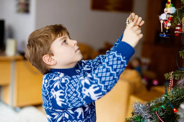 Niño bajando decoraciones navideñas del árbol de Navidad. Familia después de la celebración quitar y disponer del árbol. Niños en ropa festiva con renos. — Foto de Stock