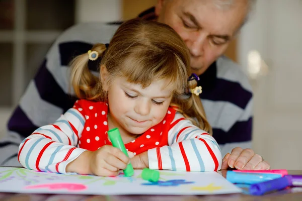 Mignon petit bébé tout-petit fille et beau grand-père senior peinture avec des stylos en feutre coloré et crayons à la maison. Petit-enfant et homme s'amusent ensemble, famille créative. — Photo