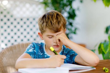 Çalışkan, mutlu okul çocuğu Corona salgınından dolayı karantina zamanında ödev yapıyor. Kalemle yazan sağlıklı bir çocuk, evde kalıyor. Evde eğitim kavramı