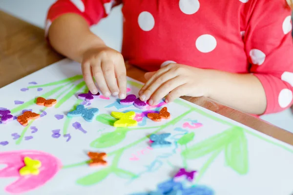 Kleines Mädchen spielt mit verschiedenen bunten Aufklebern und bemalt Blumen. Konzept der Aktivität von Kindern während der Coronavirus-Quarantäne. Kind lernt Farben bei Eltern zu Hause — Stockfoto