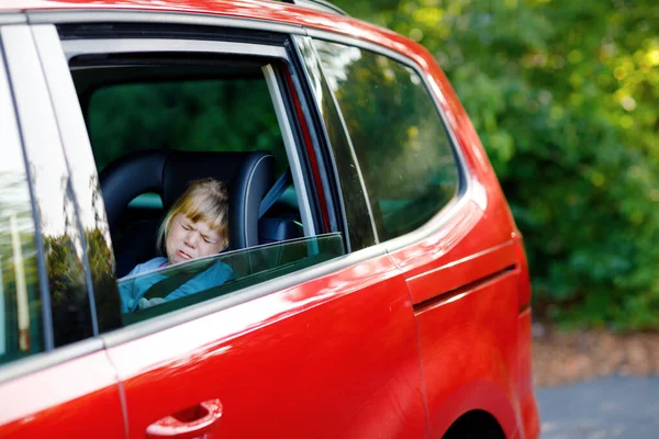 Sad upset little kid girl sitting in car in traffic jam during going for summer vacation with his parents. Tired, exhausted child not happy about long journey. Crying baby. — Stock Photo, Image