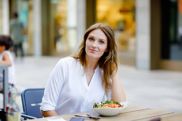 Mladá krásná žena jíst čerstvý salát ve venkovní restauraci. Žena si užívá obědovou mísu s čerstvou zeleninou. Zdravé jídlo. V letní den. — Stock fotografie