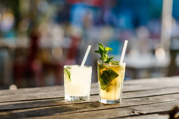 Zwei Gläser frischer alkoholischer Kühlcocktail im Sommer auf der Terrasse eines Cafés. Ein erfrischender Mojito mit Eis, Minze und Limette zur Abkühlung im heißen Sommer. — Stockfoto